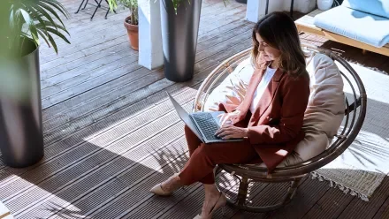 Overhead view of a woman in a suit sitting in a round chair holding a laptop